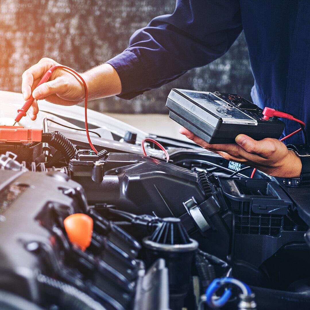 Автоэлектрик ремонтирует автомобиль